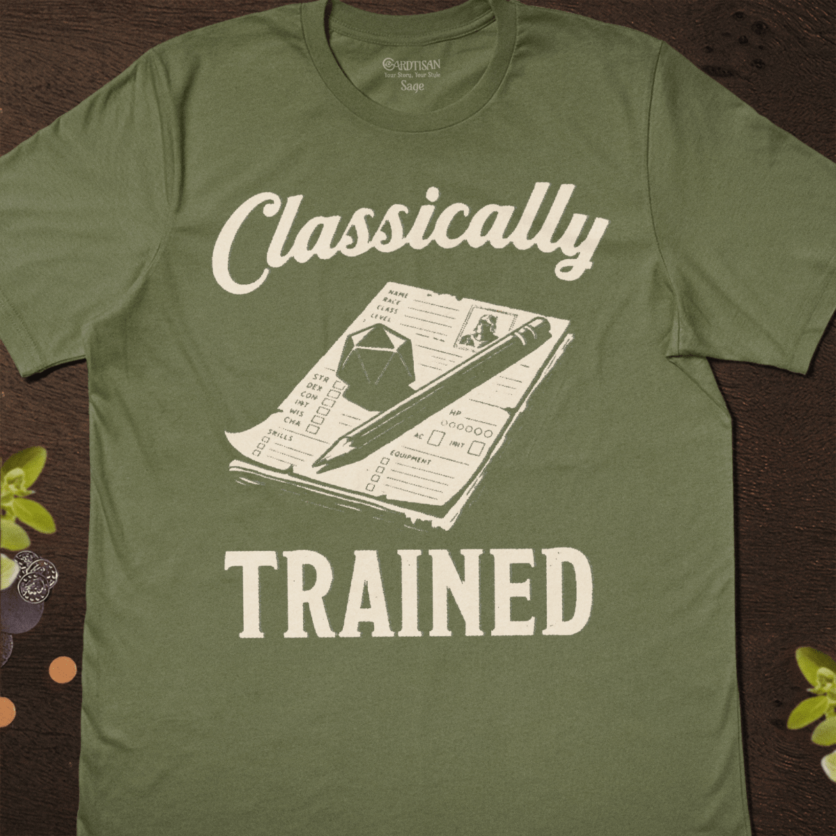 Sage green graphic T-shirt with a character sheet, pencil, and d20 illustration and "Classically Trained" text