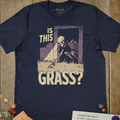 Navy blue fantasy T-shirt with a skeleton in a grassy field and is this grass text
