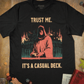 Black trading card game T-shirt with a hooded dealer and burning city illustration and Trust Me It's a Casual Deck text