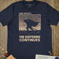 Navy dark fantasy T-shirt with a cloaked knight in a woodcut rainstorm panel and Lore Update: The Suffering Continues text