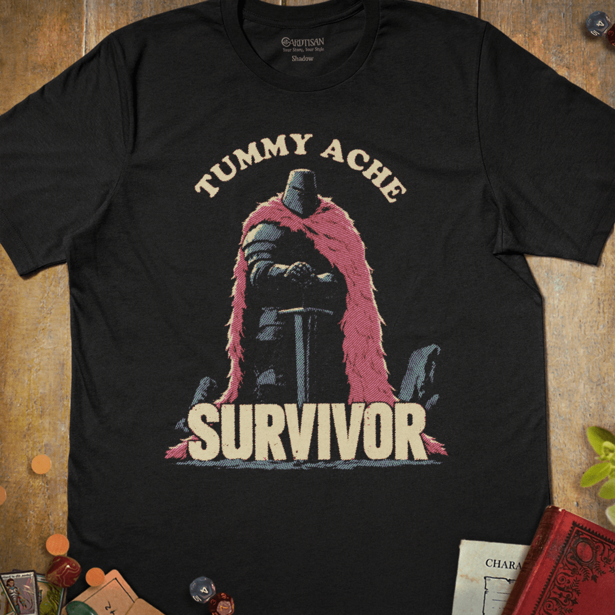 Black graphic T-shirt with an armored knight in a pink fur cloak illustration and "Tummy Ache Survivor" text